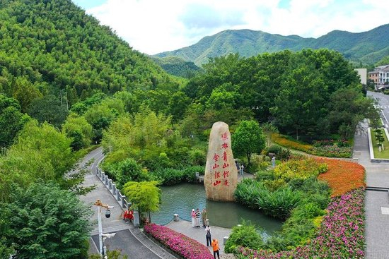  2025年8月6日，在浙江省湖州市安吉县余村，游客在刻有“绿水青山就是金山银山”的石碑前留影。新华社记者 毛竹 摄